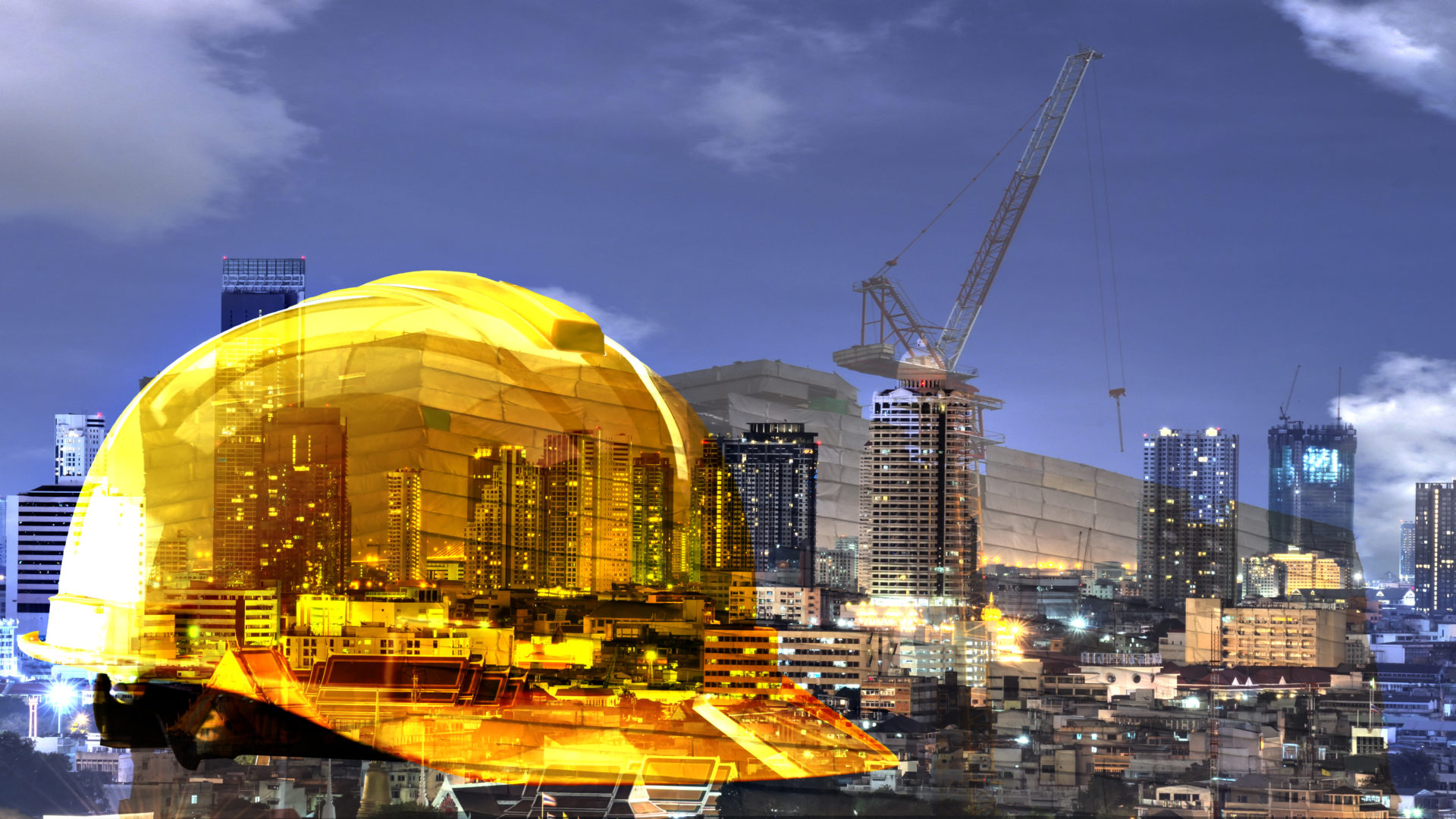 a yellow helmet for the safety of the workers, with city as a backdrop and modern building in the business district twilight time.